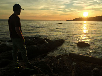 Man looking at sea against sky during sunset