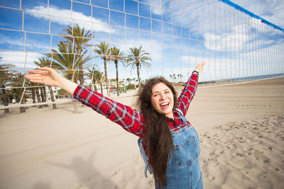 Portrait of smiling young woman with arms raised