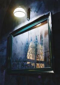 Low angle view of illuminated glass window in building