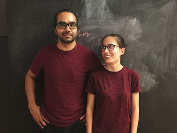 Portrait of man standing with woman against blackboard