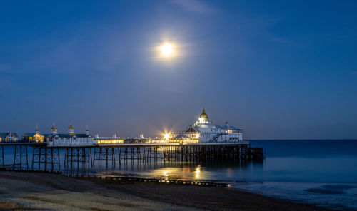 Illuminated pier over sea at night