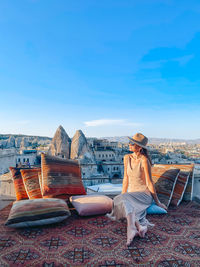 Rear view of woman sitting on field against clear blue sky