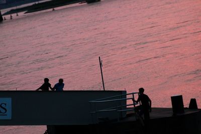 Silhouette people photographing on sea during sunset