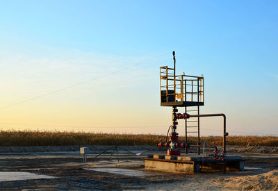 Lifeguard hut on field against clear sky during sunset