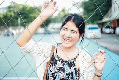 Smiling woman seen through net in court