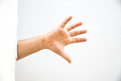 Cropped hand of man showing stop gesture against wall