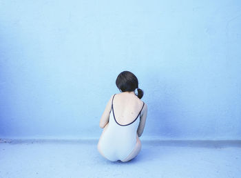 Woman sitting in front of blue wall