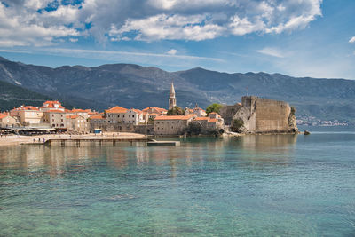 Buildings by sea against sky