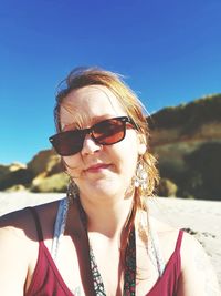 Portrait of woman wearing sunglasses at beach during sunny day