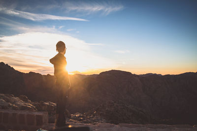 Side view of man standing on mountain during sunset