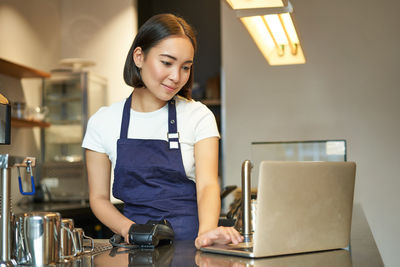 Portrait of young woman using mobile phone while sitting at home