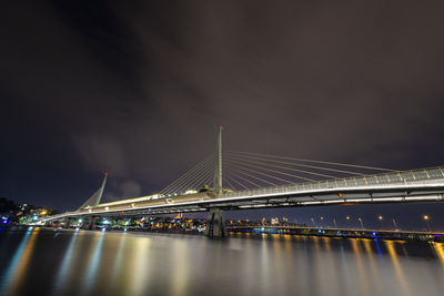 Illuminated bridge over river at night