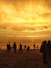 Silhouette people on beach against sky during sunset