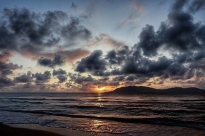 Scenic view of sea against dramatic sky during sunset