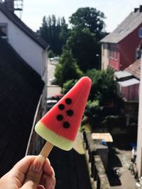 Close-up of hand holding ice cream against buildings