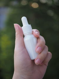 Close-up of hand holding bottle against blurred background