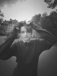 Young woman with arms raised standing outdoors