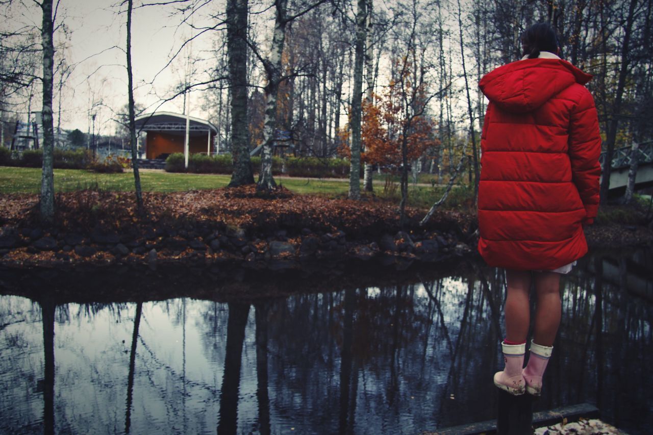 REAR VIEW OF WOMAN STANDING ON LAKE