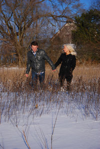 Full length of smiling woman with bare trees in winter