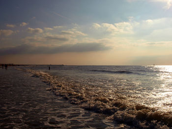 View of calm beach against cloudy sky