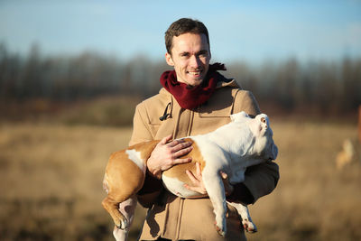 Portrait of smiling young man with dog standing on land