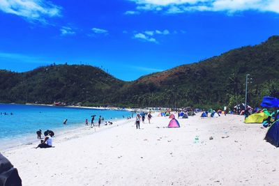 People at beach against blue sky