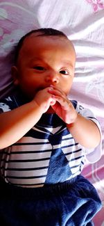 High angle view of cute baby lying on bed at home