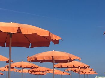 Low angle view of parasols against clear blue sky