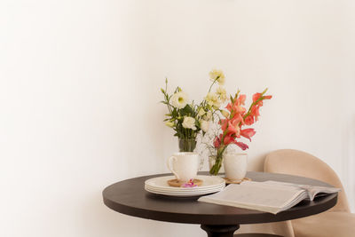 Flowers and magazine near dishware on table