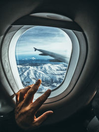 Cropped hand touching airplane window