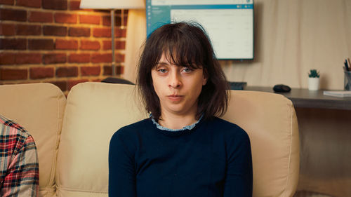 Portrait of young woman sitting on sofa at home