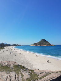 Scenic view of beach against clear blue sky