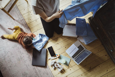 Directly above shot of businesswoman examining shirt by toddler at home