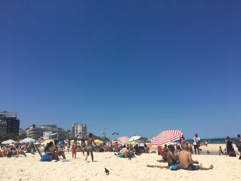 People enjoying at beach against clear sky