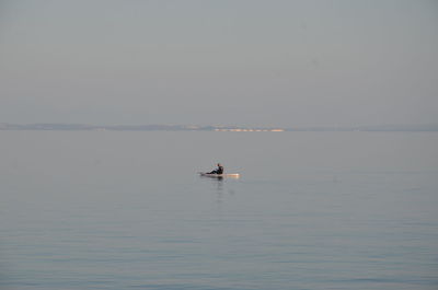 Man paddleboarding in sea against clear sky