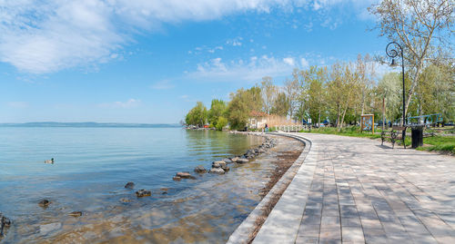 Footpath by lake against sky