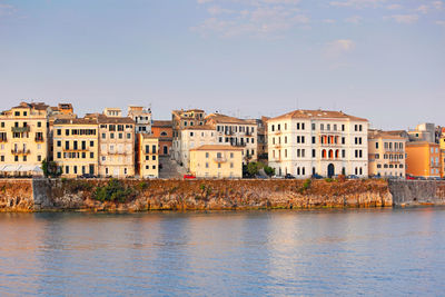 Buildings by sea against clear sky