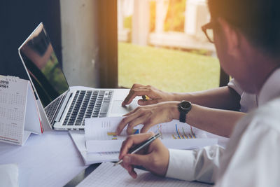 Midsection of man using mobile phone while sitting on table