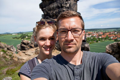 Portrait of smiling young couple standing against landscape