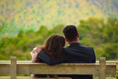 Rear view of couple sitting on bench