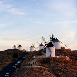 Traditional windmill by road against sky