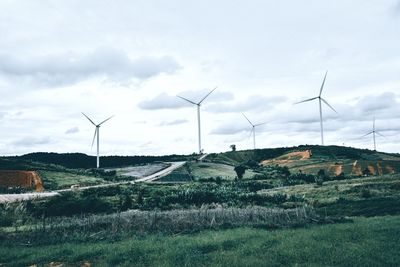 Wind turbines on field against sky