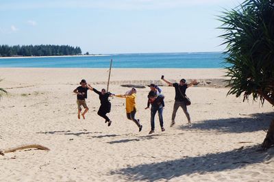 People playing at beach against sky