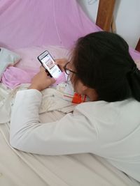 Midsection of woman using mobile phone on bed