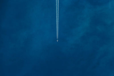 Airplane flying against vapor trail in sky