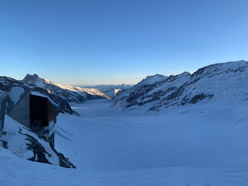 Scenic view of snow covered mountains against clear blue sky