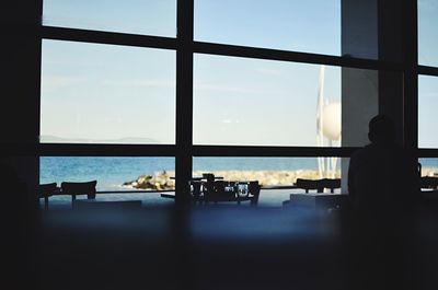 Rear view of silhouette man sitting by window