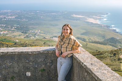 Portrait of young woman standing against mountain