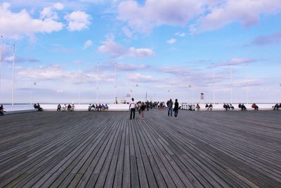 People on pier over sea against sky