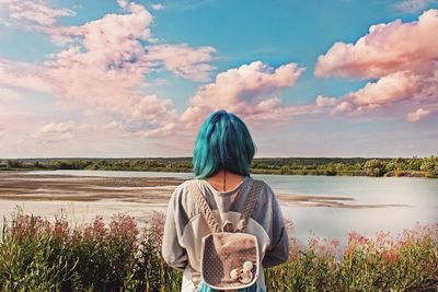 Rear view of woman standing in front of lake